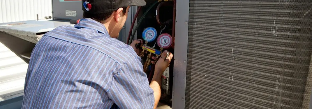 HVAC technician servicing a condenser unit in Mentone