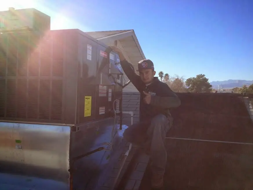 HVAC technician performing Air Duct Cleaning on a rooftop unit in Mentone